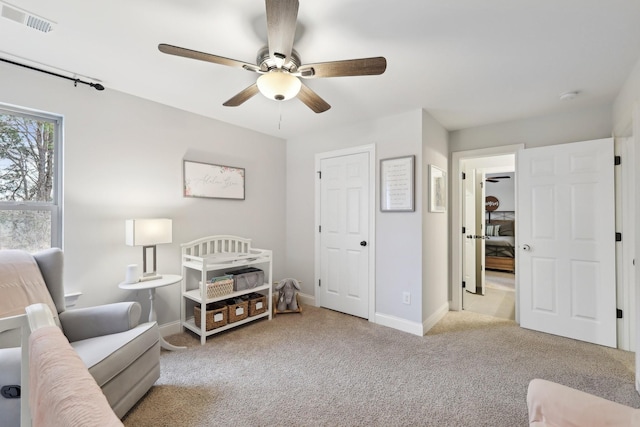 living area with visible vents, baseboards, carpet, and a ceiling fan