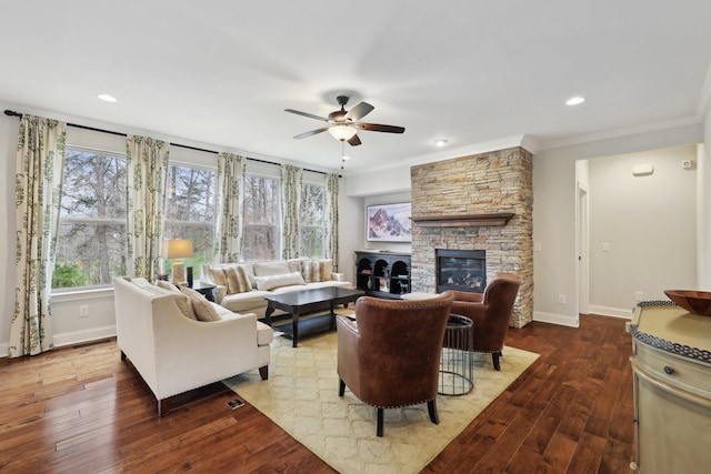 living room with baseboards, wood-type flooring, a stone fireplace, and a ceiling fan