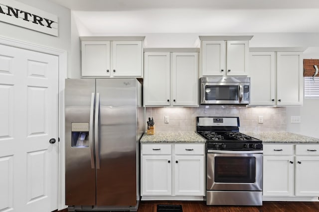 kitchen with white cabinets, light stone counters, backsplash, and stainless steel appliances