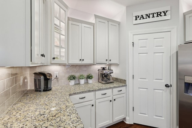 kitchen with decorative backsplash, stainless steel fridge with ice dispenser, and white cabinetry
