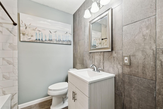 bathroom featuring a shower, toilet, vanity, and baseboards