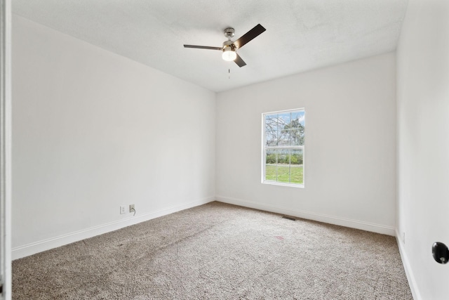 empty room with visible vents, baseboards, carpet floors, and ceiling fan