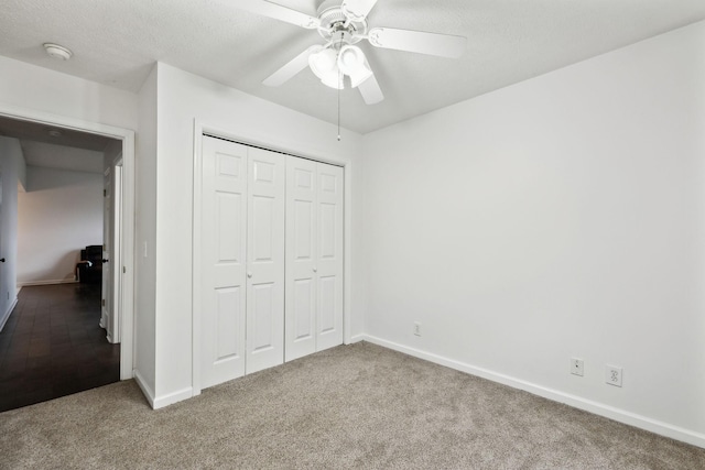 unfurnished bedroom with a textured ceiling, a closet, carpet, baseboards, and ceiling fan