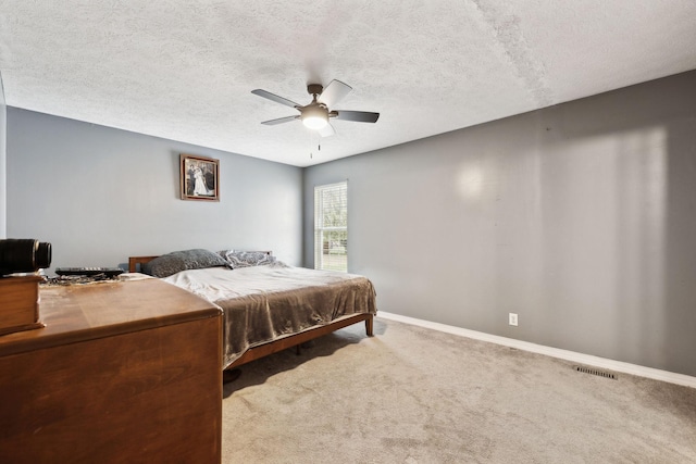 carpeted bedroom featuring visible vents, baseboards, a textured ceiling, and ceiling fan