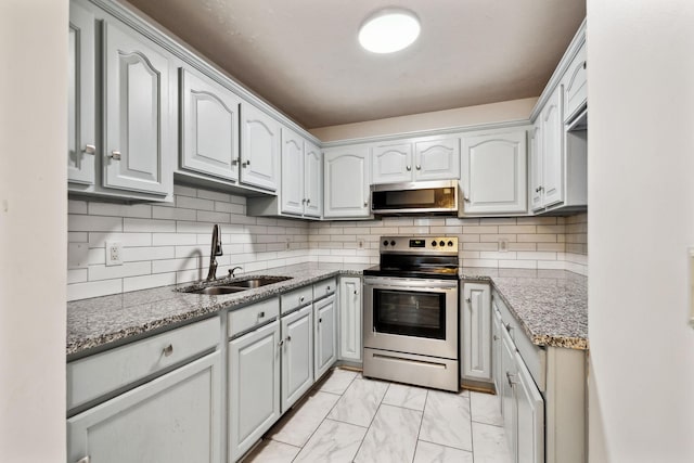 kitchen with light stone counters, marble finish floor, stainless steel appliances, and a sink