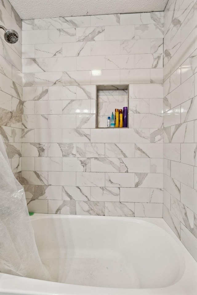 full bathroom featuring shower / bath combo and a textured ceiling