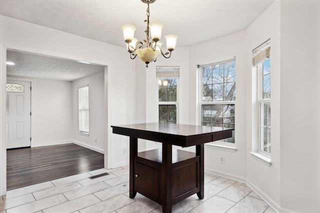 unfurnished dining area featuring a notable chandelier, a healthy amount of sunlight, and baseboards