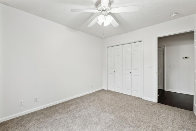 unfurnished bedroom with a closet, dark carpet, a ceiling fan, and baseboards
