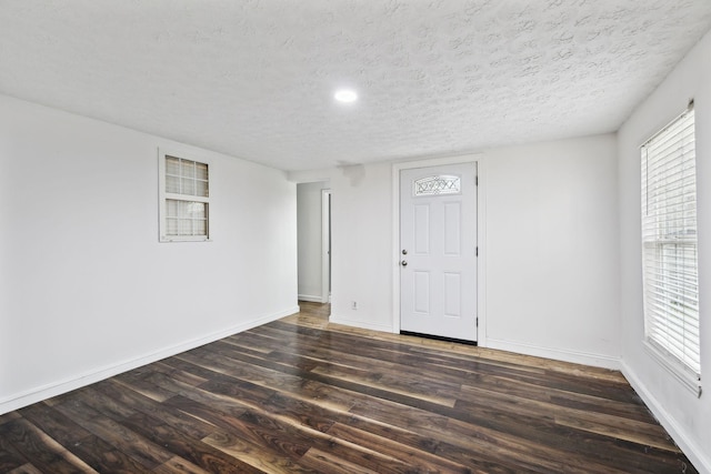 unfurnished room with wood finished floors, baseboards, and a textured ceiling
