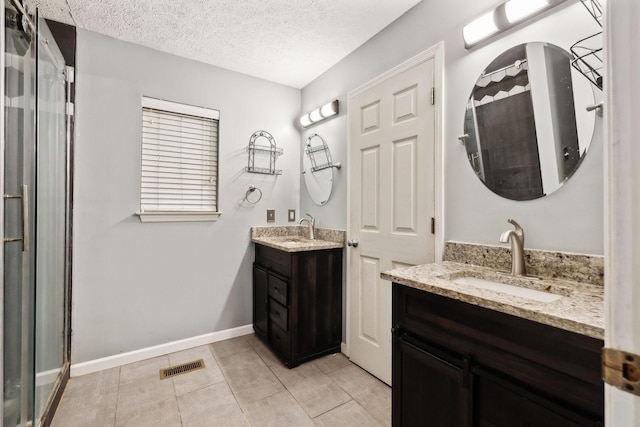bathroom with a sink, visible vents, a shower with shower door, and a textured ceiling