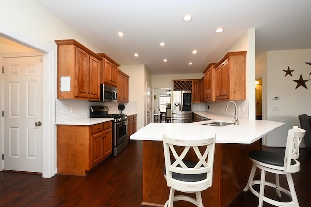 kitchen with a kitchen bar, a peninsula, tasteful backsplash, a sink, and stainless steel appliances