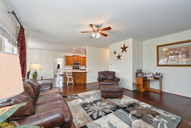 living area featuring dark wood-type flooring, baseboards, and a ceiling fan