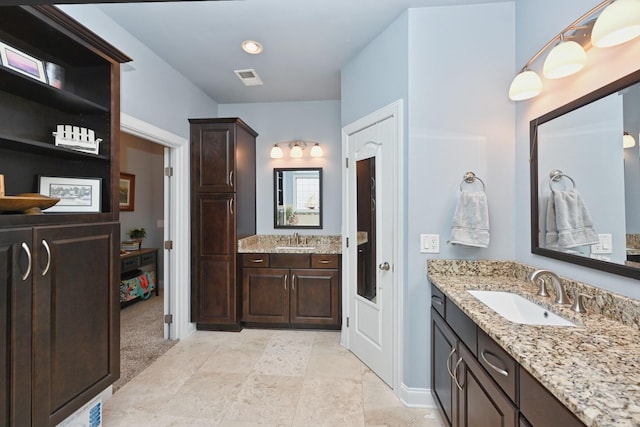 full bath with two vanities, a sink, and visible vents