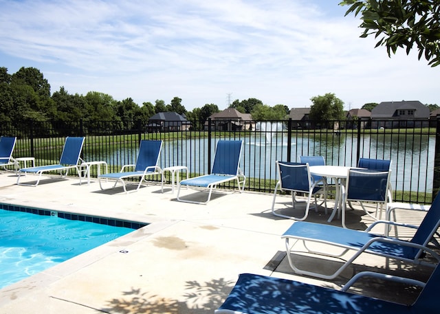 view of swimming pool with a water view, fence, and a patio