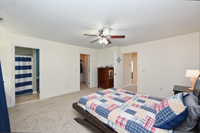 bedroom featuring light carpet, ceiling fan, baseboards, and a walk in closet