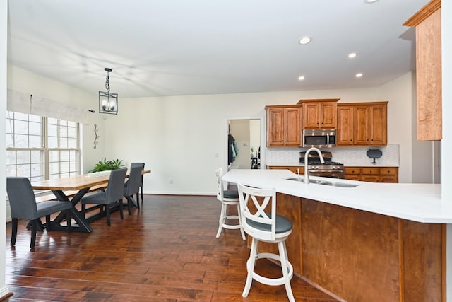 kitchen featuring a sink, light countertops, brown cabinetry, stainless steel appliances, and backsplash