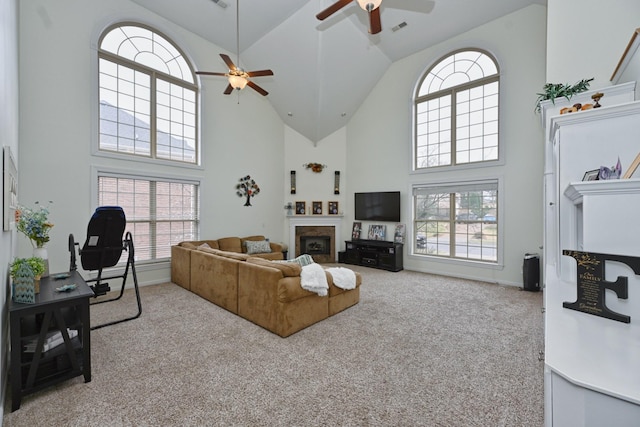 carpeted living room featuring baseboards, a fireplace, a ceiling fan, visible vents, and high vaulted ceiling