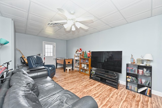 living room with an ornate ceiling, ceiling fan, wood finished floors, and baseboards
