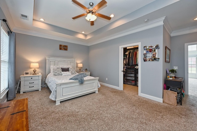bedroom with ornamental molding, visible vents, a walk in closet, and carpet