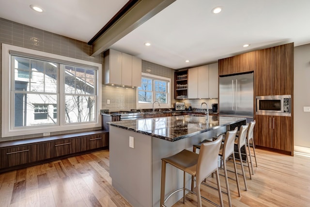 1926 20th Ave S, Nashville, TN 37212 - kitchen with modern cabinets, tasteful backsplash, light wood-style floors, wall chimney range hood, and built in appliances