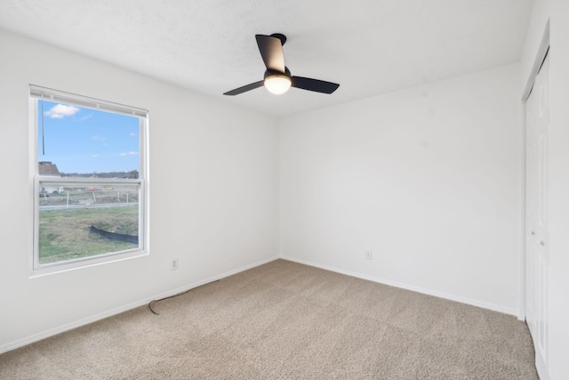 carpeted spare room with baseboards and ceiling fan