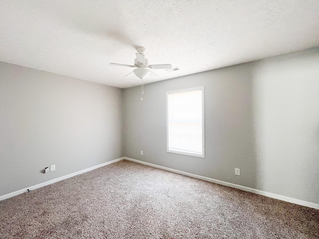 carpeted spare room featuring visible vents, baseboards, a textured ceiling, and ceiling fan