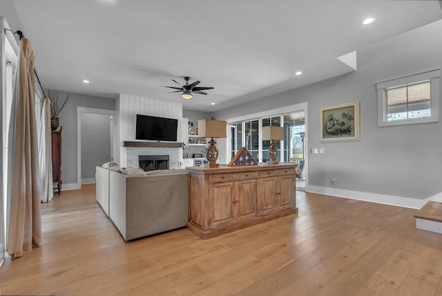 living area featuring recessed lighting, a large fireplace, light wood-style flooring, and a ceiling fan