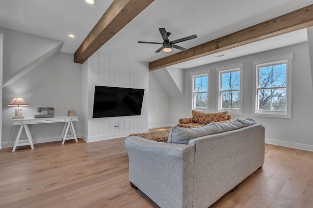 living area with a large fireplace, ceiling fan, baseboards, beam ceiling, and wood finished floors