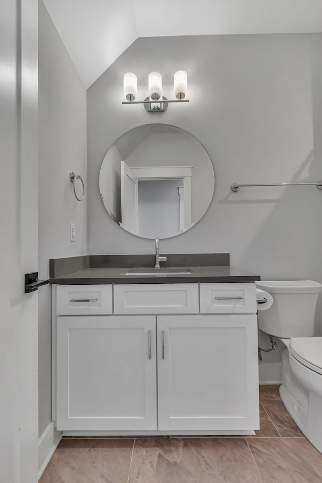 half bath with toilet, vanity, and vaulted ceiling