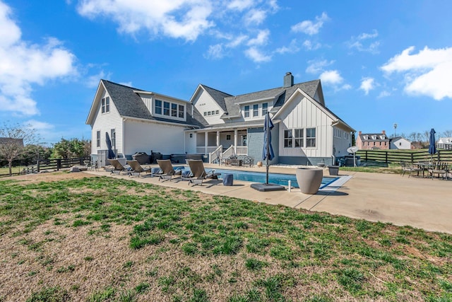 back of property featuring fence, a patio area, board and batten siding, and a chimney