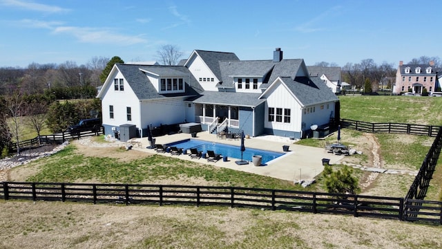 back of property featuring board and batten siding, roof with shingles, a chimney, a fenced backyard, and a patio area