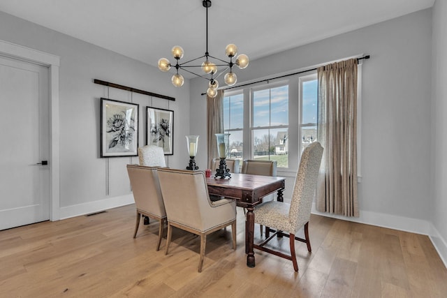 dining area with a notable chandelier, light wood-style flooring, visible vents, and baseboards