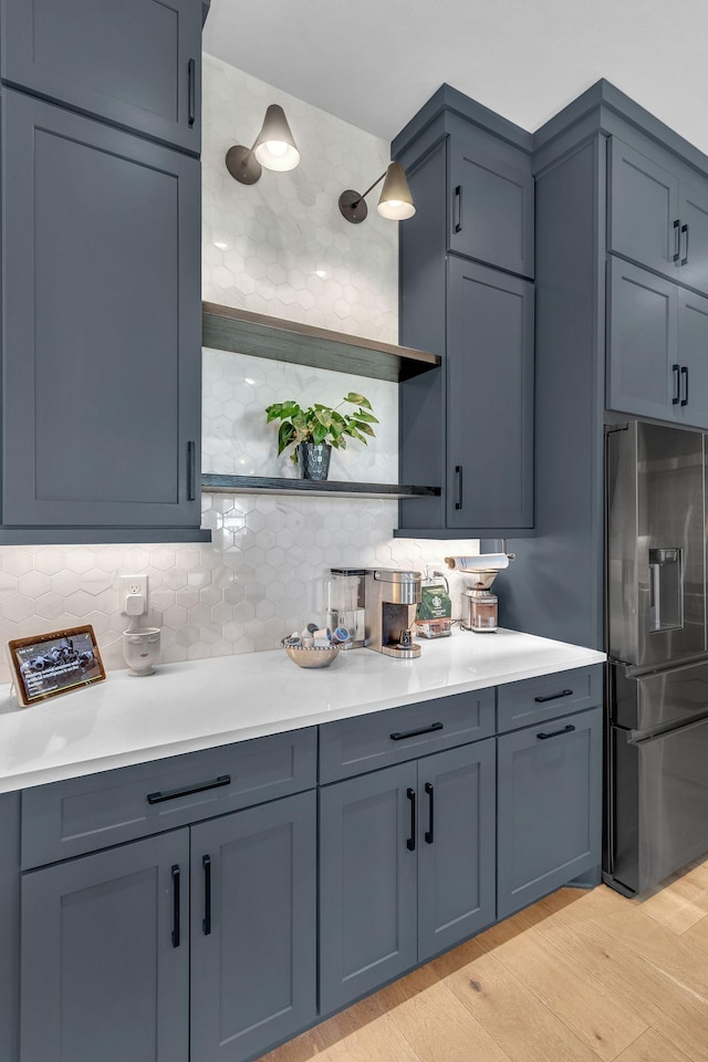kitchen with tasteful backsplash, open shelves, light countertops, and stainless steel fridge with ice dispenser