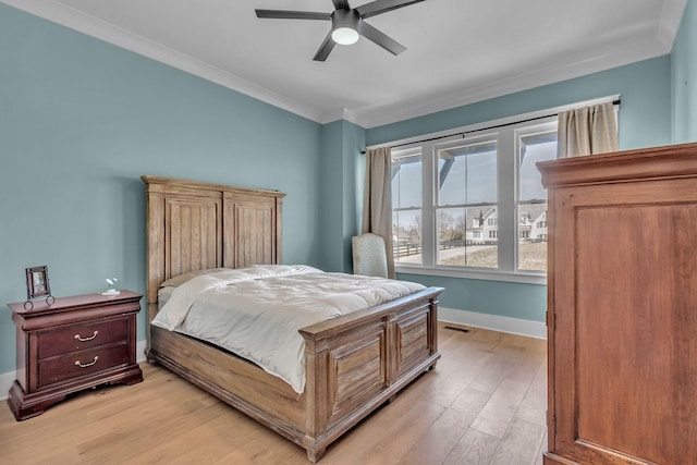 bedroom featuring crown molding, baseboards, light wood-type flooring, and ceiling fan