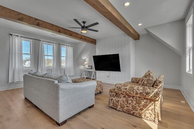living room featuring beam ceiling, a healthy amount of sunlight, light wood-style flooring, and a ceiling fan