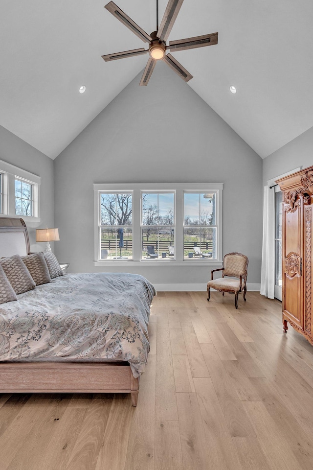 bedroom featuring light wood-style flooring, a ceiling fan, baseboards, and high vaulted ceiling