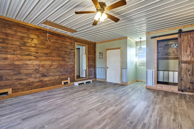 interior space featuring ceiling fan, a barn door, and wood finished floors
