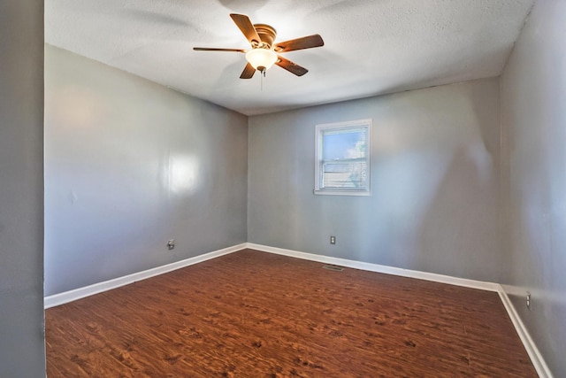 unfurnished room with a textured ceiling, dark wood-type flooring, baseboards, and ceiling fan