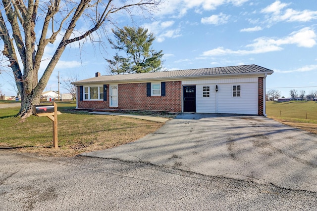 ranch-style home featuring a front lawn, a chimney, brick siding, and aphalt driveway