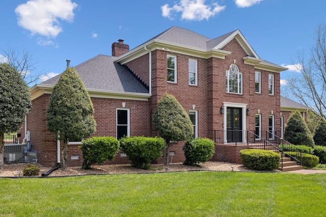back of house with a chimney, brick siding, a yard, and roof with shingles