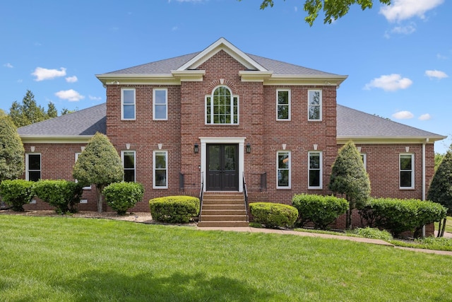 view of front of property with brick siding, a shingled roof, and a front yard