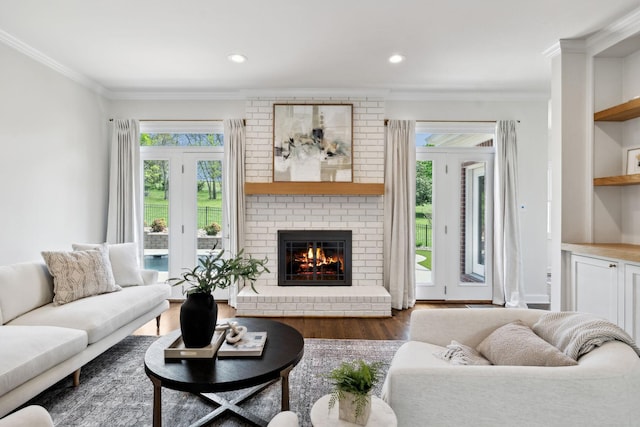 living area with a fireplace, wood finished floors, ornamental molding, and recessed lighting