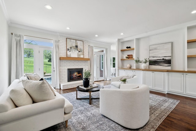 living room with recessed lighting, dark wood-type flooring, crown molding, a fireplace, and built in features