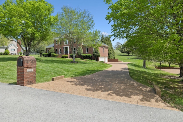 colonial inspired home featuring an attached garage, driveway, and a front yard