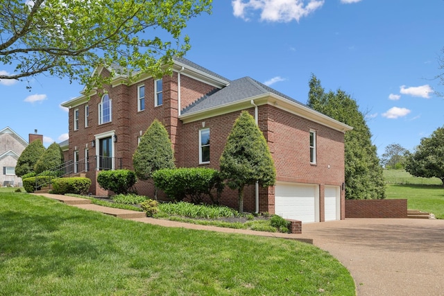 view of side of property with brick siding, driveway, a yard, and a garage