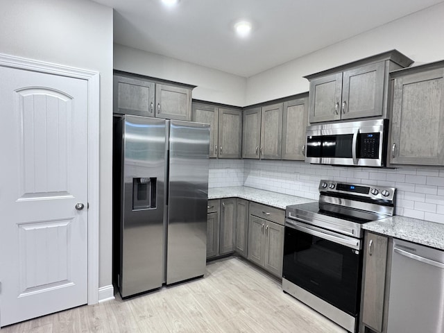 443 Generosity Way, Smyrna, TN 37167 - kitchen featuring stainless steel appliances, tasteful backsplash, light wood-style flooring, and light stone counters