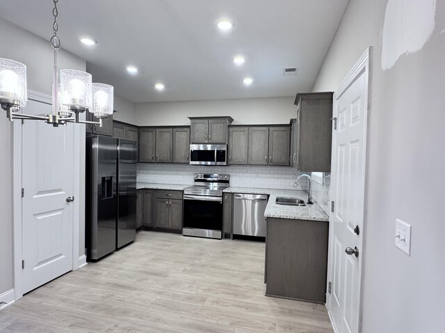 443 Generosity Way, Smyrna, TN 37167 - kitchen featuring appliances with stainless steel finishes, a sink, a chandelier, decorative backsplash, and light wood-type flooring