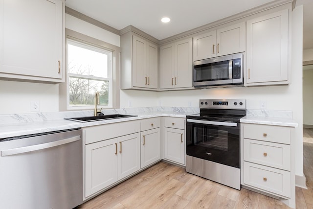 kitchen featuring a sink, recessed lighting, light wood finished floors, and stainless steel appliances