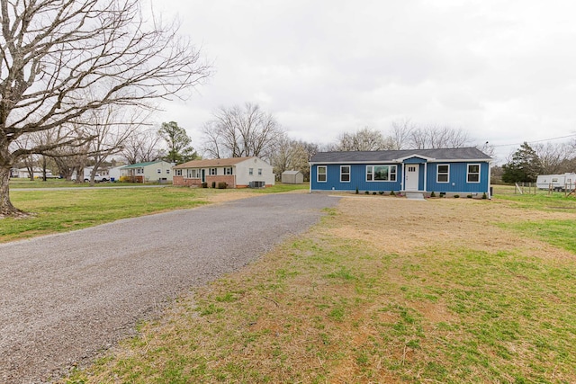 ranch-style home with gravel driveway and a front lawn