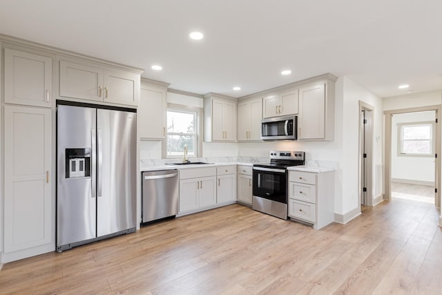 kitchen featuring a healthy amount of sunlight, light wood-style flooring, a sink, stainless steel appliances, and light countertops